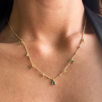 Gold-plated sterling silver necklace with small green cubic zirconia and clear stone charms worn around the neck