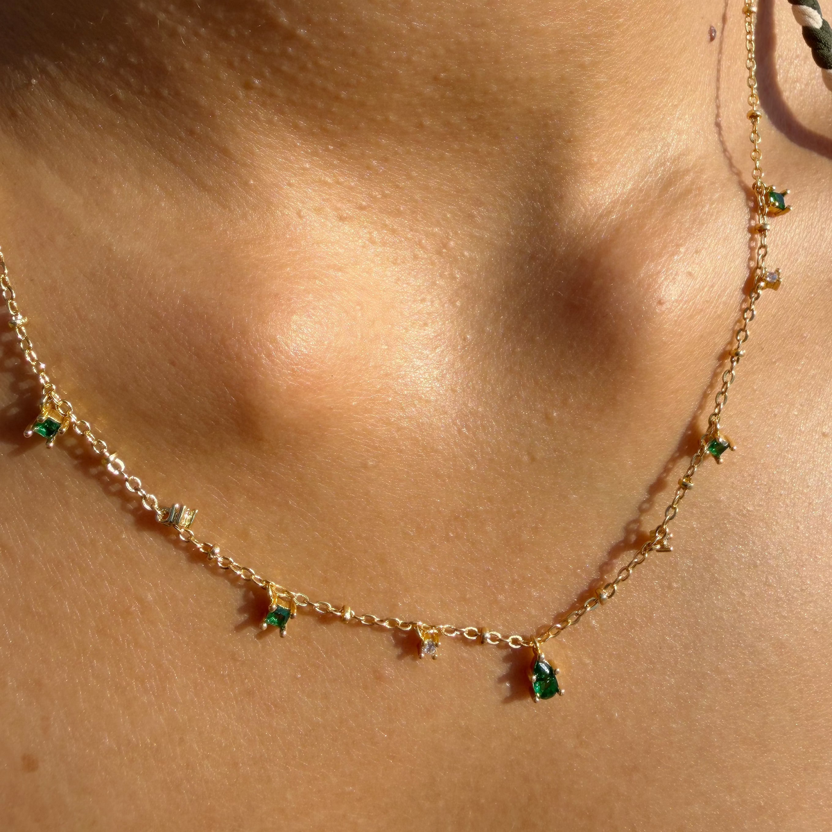 Gold-plated sterling silver necklace with small green cubic zirconia and clear stone charms worn around the neck