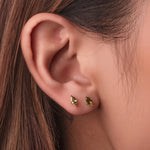 Gold-plated sterling silver stud earrings with green marquise-cut cubic zirconia stones on a light background worn on ear