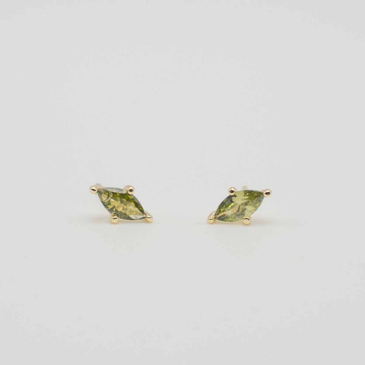 Gold-plated sterling silver stud earrings with green marquise-cut cubic zirconia stones on a light background
