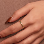 Gold-plated sterling silver delicate band ring with small green stones worn on the finger