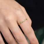 Gold-plated sterling silver delicate band ring with small green stones worn on the finger