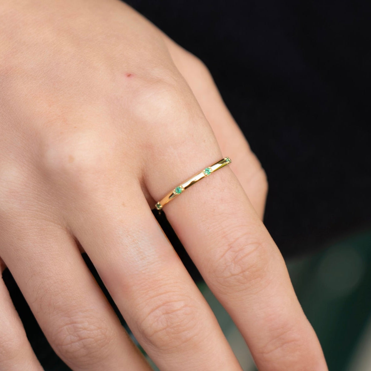 Gold-plated sterling silver delicate band ring with small green stones worn on the finger