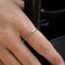 Gold-plated sterling silver delicate band ring with small green stones worn on the finger