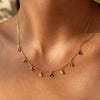 Gold-plated sterling silver necklace with small multicolour gemstone charms worn around the neck