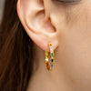 Gold-plated sterling silver hoop earrings with multicolor cubic zirconia stones worn on the ear
