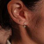 Gold-plated sterling silver stud earrings with opal flower details and clear cubic zirconia worn on ear