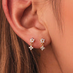 Gold-plated sterling silver stud earrings with opal flower details and clear cubic zirconia drops worn on the ear