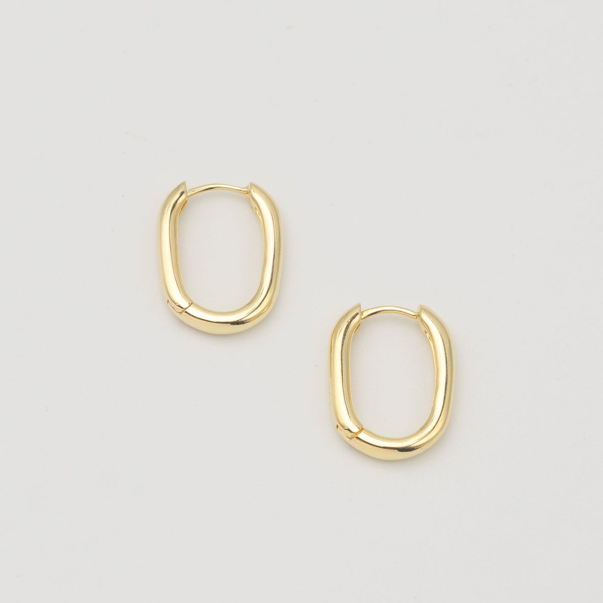 Gold-plated sterling silver oval hoop earrings with a smooth polished finish on a light background