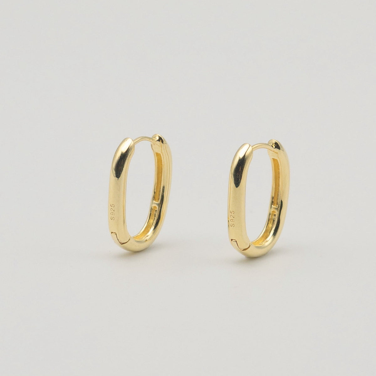 Gold-plated sterling silver oval hoop earrings with a smooth polished finish on a light background