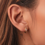 Gold-plated sterling silver huggie earrings with clear cubic zirconia pavé stones and a small clover detail