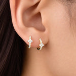 Gold-plated sterling silver huggie earrings with clear cubic zirconia pavé stones and a small clover detail