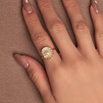 Gold-plated sterling silver ring with a central pearl surrounded by clear cubic zirconia details, worn on the finger