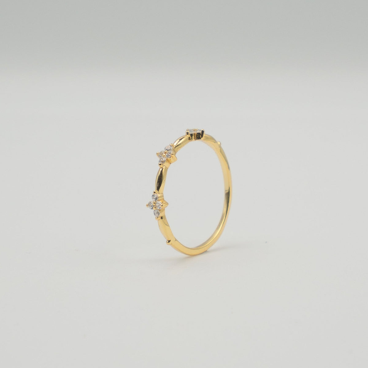 Gold-plated sterling silver ring with three small clover-shaped clear cubic zirconia details 