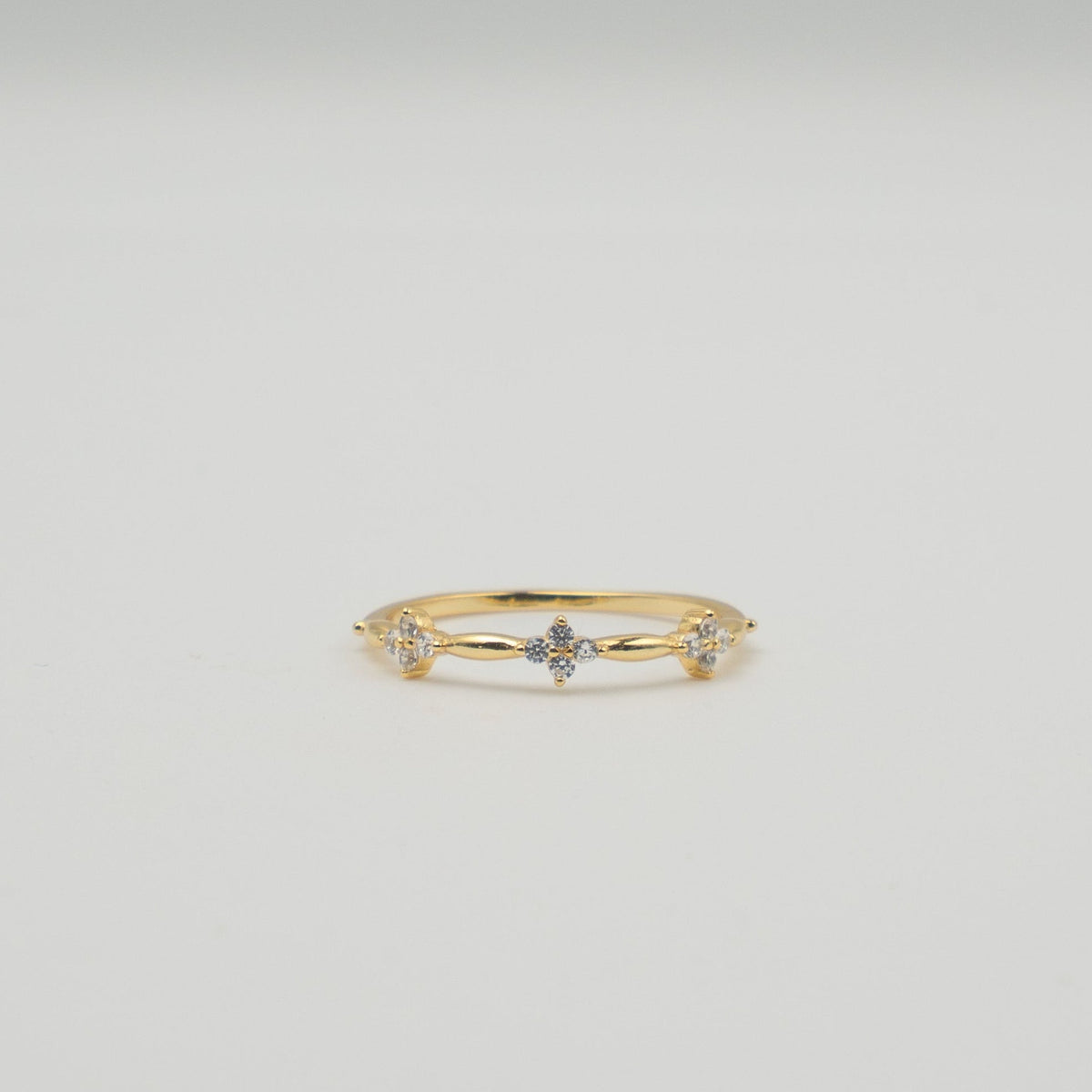 Gold-plated sterling silver ring with three small clover-shaped clear cubic zirconia details worn on the finger