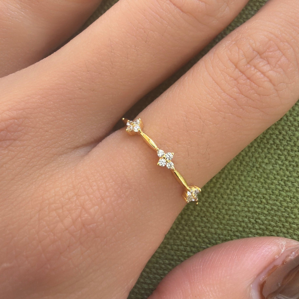 Gold-plated sterling silver ring with three small clover-shaped clear cubic zirconia details worn on the finger