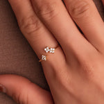 Gold-plated sterling silver ring with three flower motifs set with clear cubic zirconia stones, worn on the finger