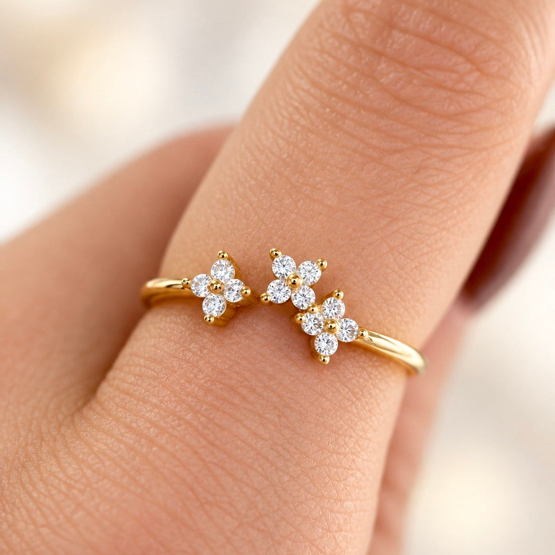 Gold-plated sterling silver ring with three flower motifs set with clear cubic zirconia stones, worn on the finger