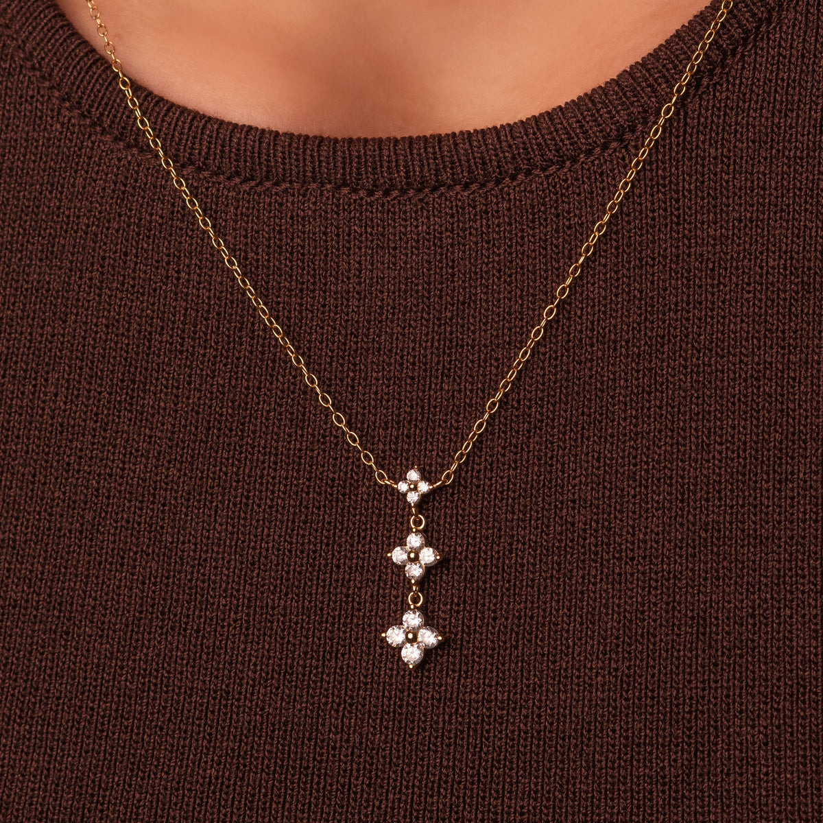 Gold-plated sterling silver drop necklace with three clear cubic zirconia flower motifs worn around the neck