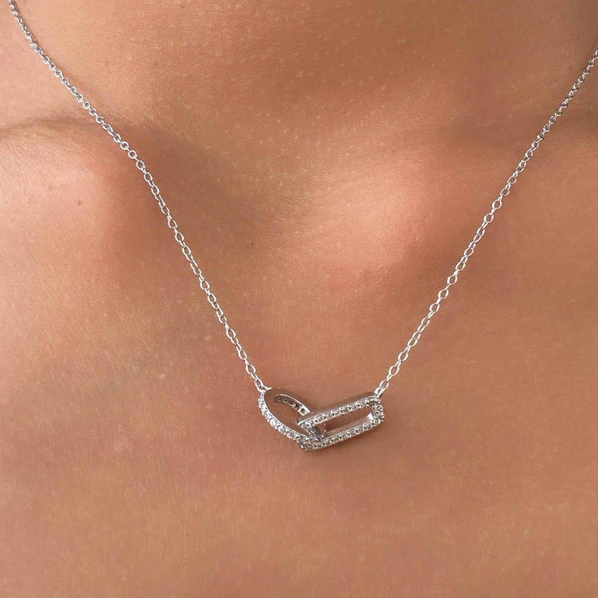 Rhodium-plated sterling silver necklace with interlocking double heart pendant and cubic zirconia stones worn on the neck