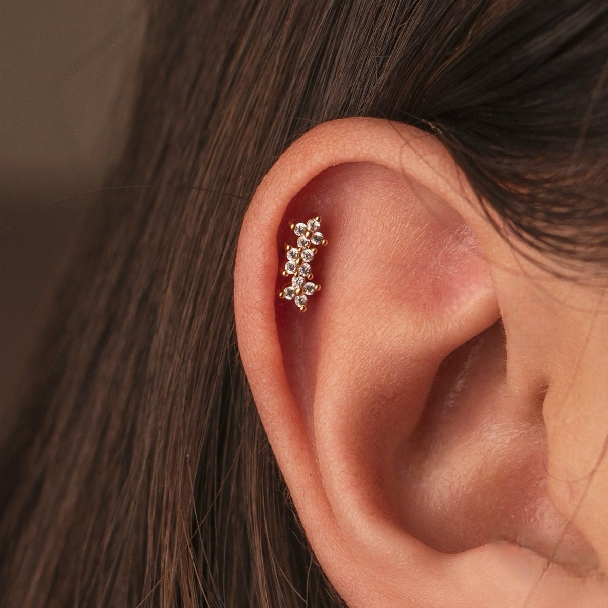 Gold-plated stainless steel cartilage earring with clustered clear cubic zirconia stones worn on the upper ear