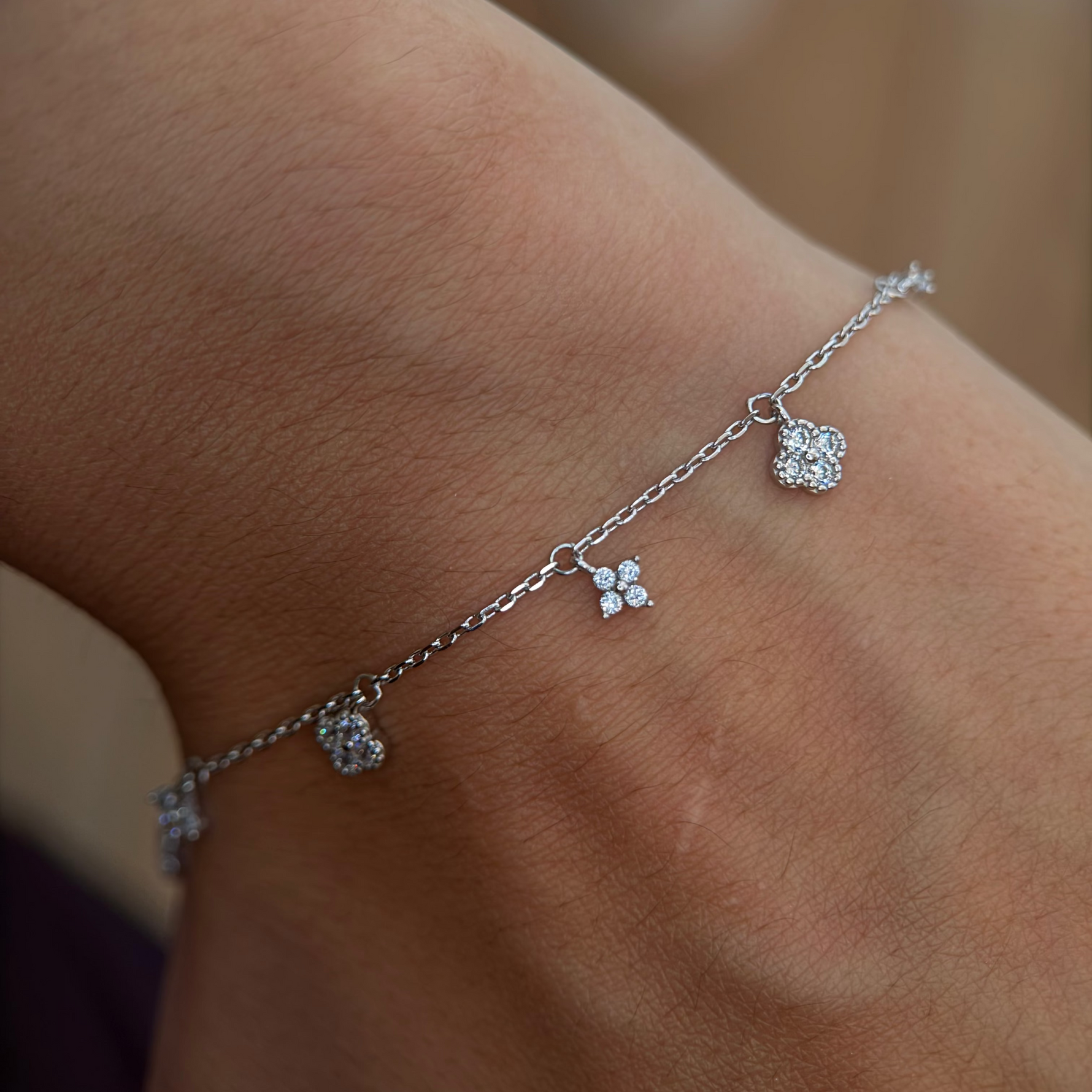 Rhodium-plated 925 sterling silver bracelet with cubic zirconia flower charms worn on the wrist