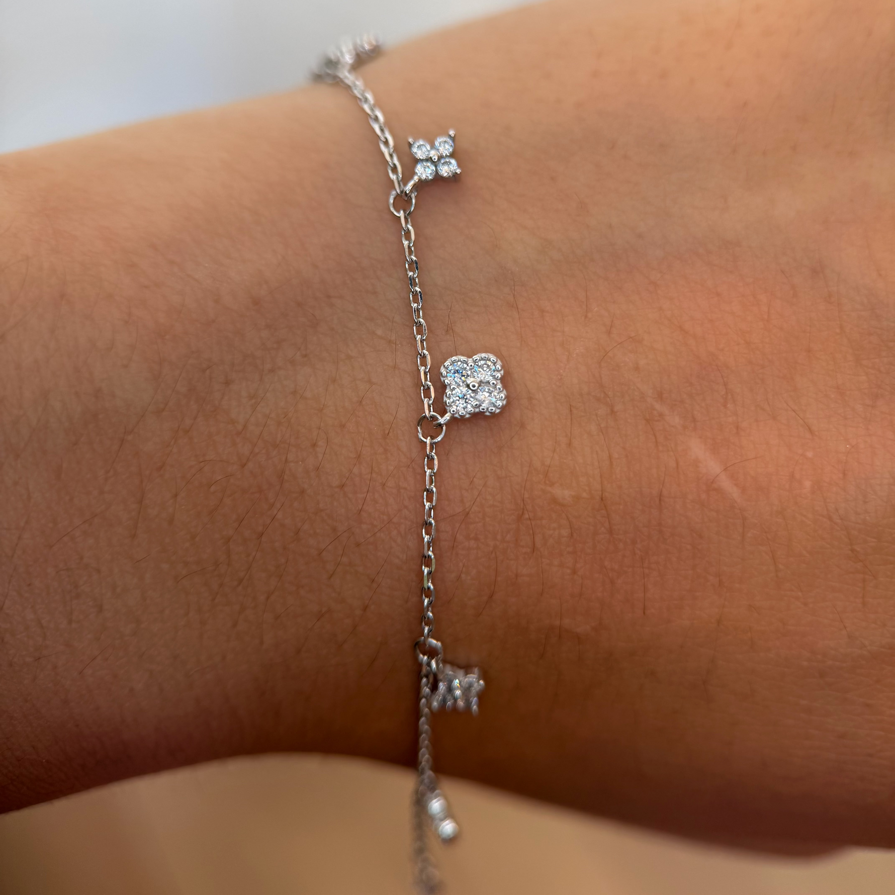 Rhodium-plated 925 sterling silver bracelet with cubic zirconia flower charms worn on the wrist