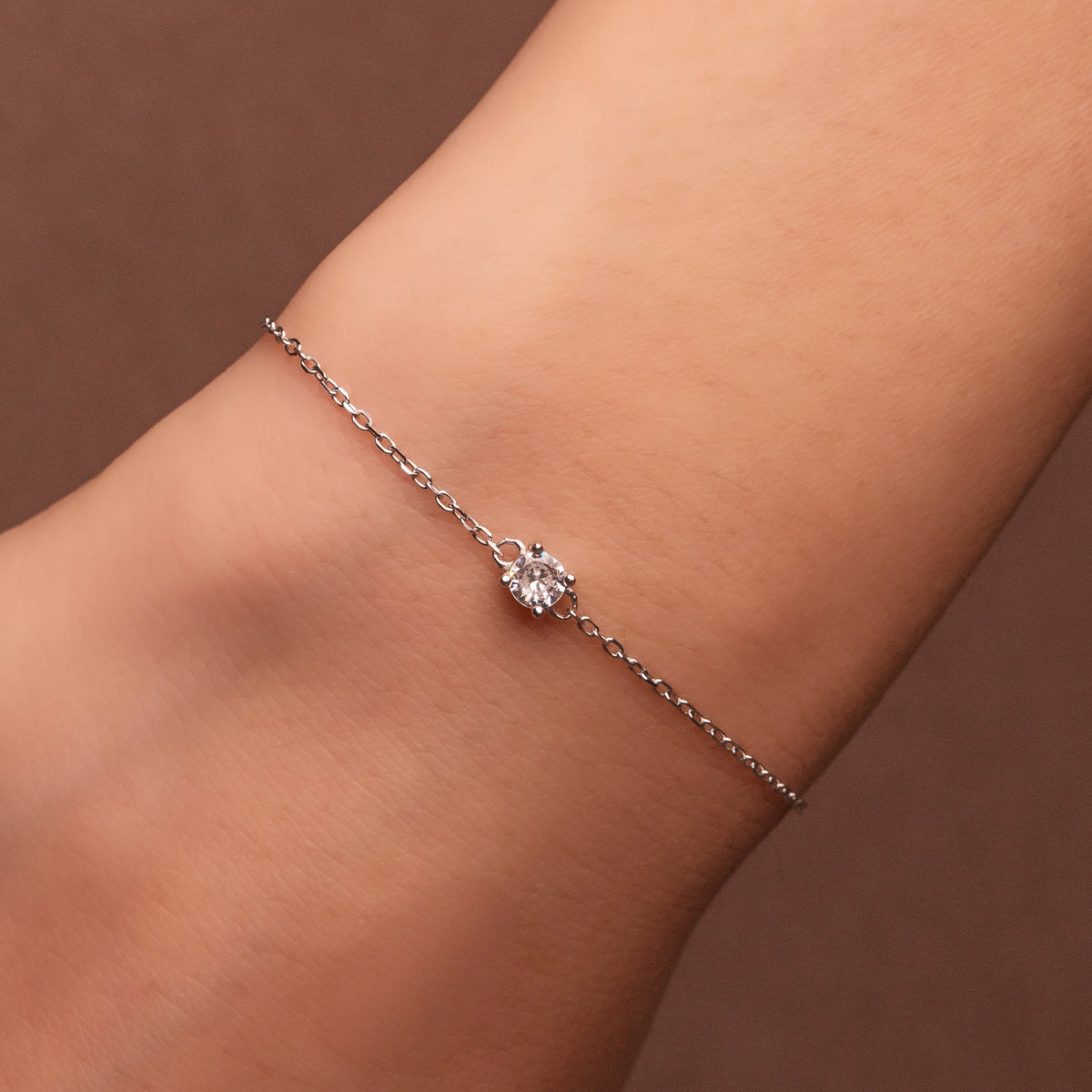 Rhodium-plated 925 sterling silver bracelet with a round cubic zirconia solitaire worn on wrist