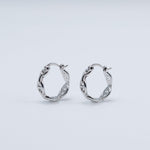 Rhodium-plated sterling silver hoop earrings with an interlocking chain-link design on a light background