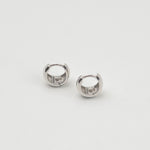 Rhodium-plated sterling silver chunky huggie earrings with a smooth polished finish on a light background