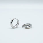 Rhodium-plated sterling silver chunky huggie earrings with a smooth polished finish on a light background