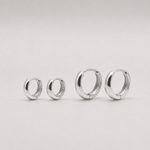 Rhodium-plated sterling silver chunky huggie earrings with a smooth polished finish on a light background