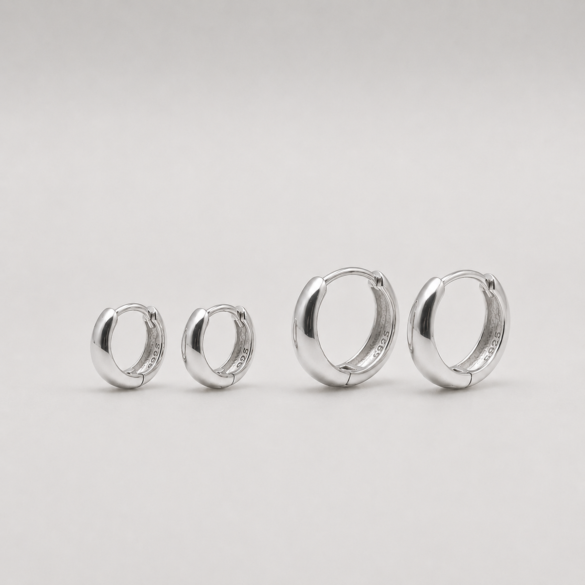 Rhodium-plated sterling silver chunky huggie earrings with a smooth polished finish on a light background