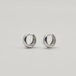 Rhodium-plated sterling silver chunky huggie earrings with a smooth polished finish on a light background