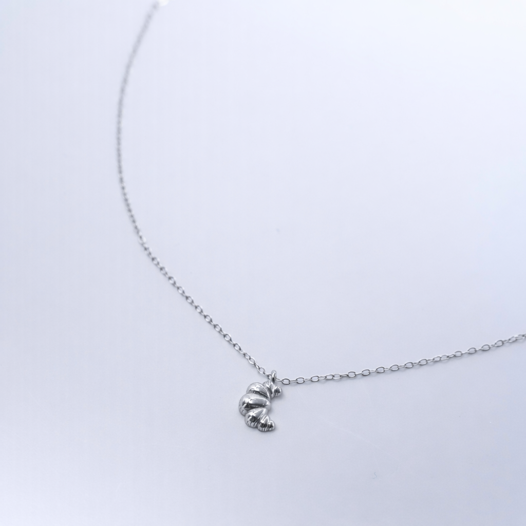 Rhodium-plated sterling silver necklace with a small croissant pendant on a white background