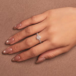Rhodium-plated sterling silver solitaire ring with a cushion-cut moissanite center stone and pavé band worn on the finger