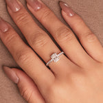 Rhodium-plated sterling silver solitaire ring with a cushion-cut moissanite center stone and pavé band worn on the finger