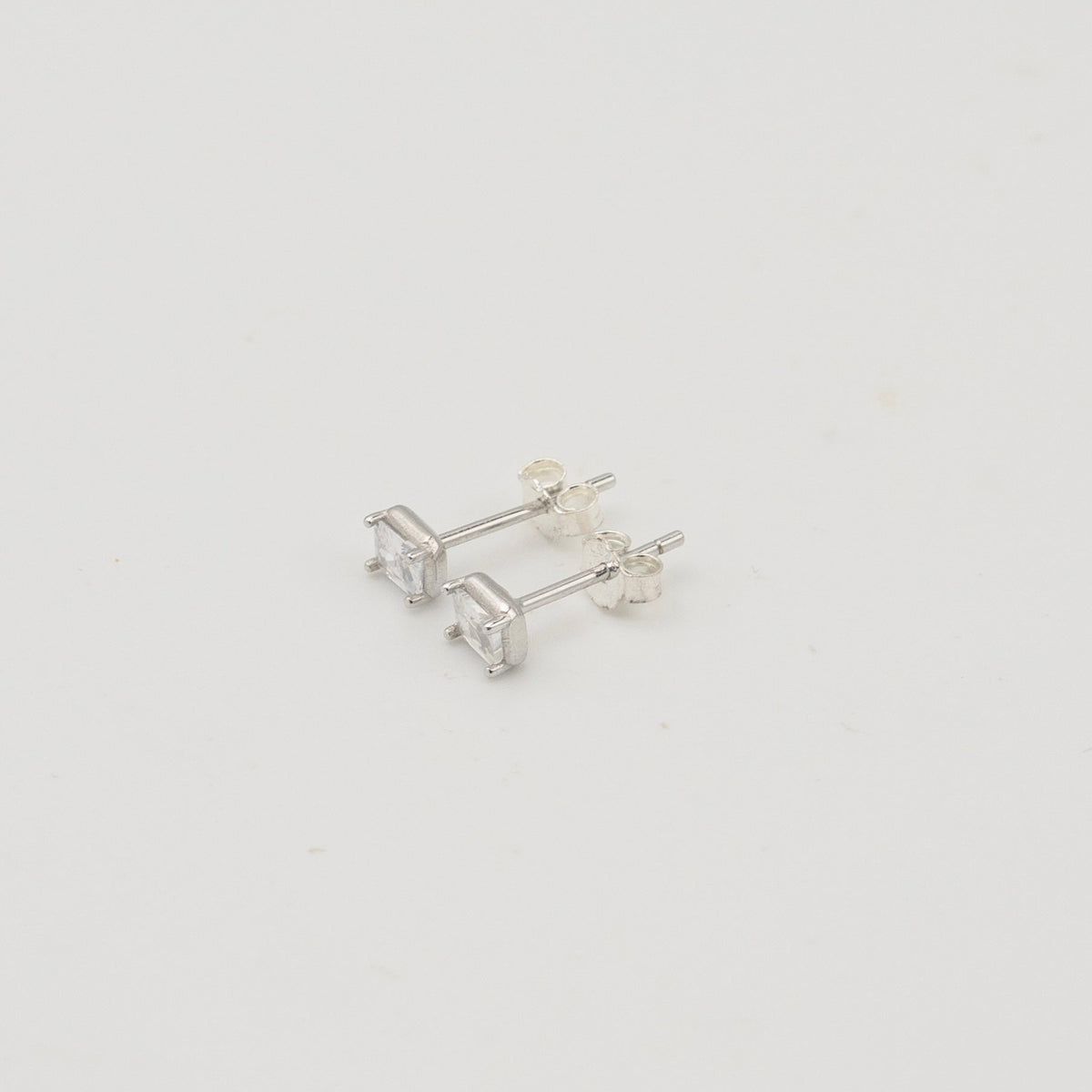 Rhodium-plated sterling silver stud earrings with emerald-cut clear cubic zirconia stones on a light background