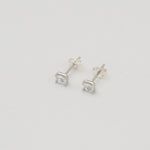Rhodium-plated sterling silver stud earrings with emerald-cut clear cubic zirconia stones on a light background