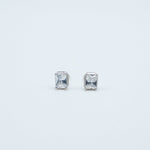 Rhodium-plated sterling silver stud earrings with emerald-cut clear cubic zirconia stones on a light background