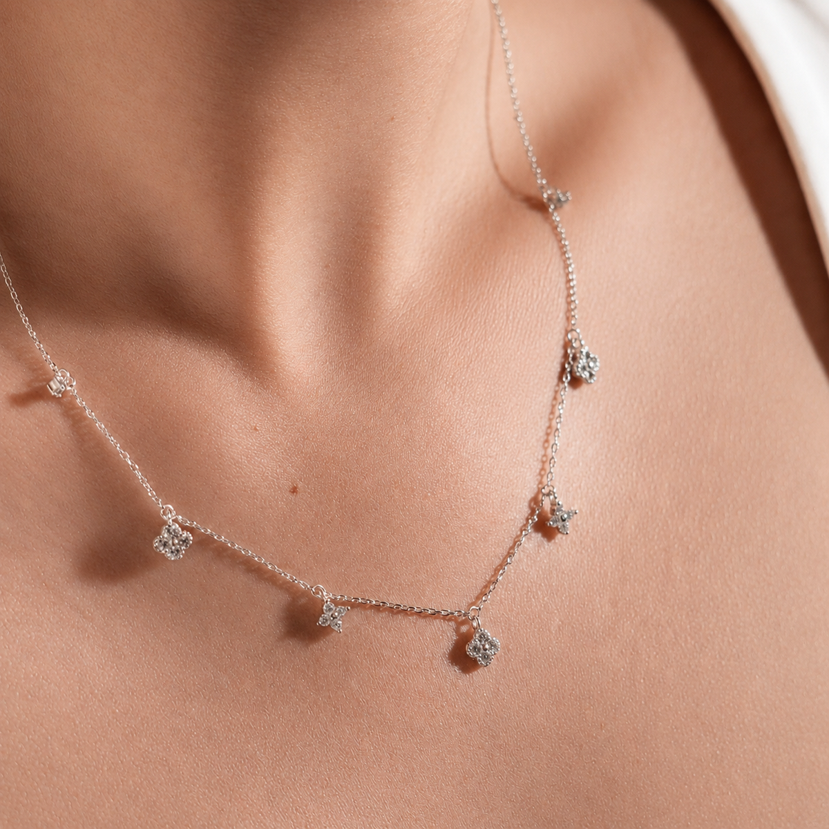 Rhodium-plated sterling silver necklace with delicate cubic zirconia flower charms worn on the neck