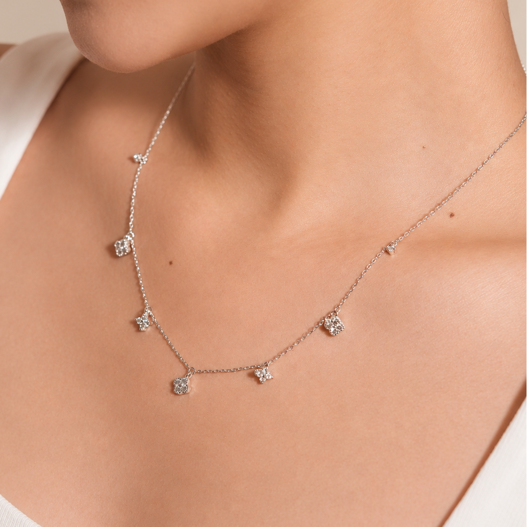 Rhodium-plated sterling silver necklace with delicate cubic zirconia flower charms worn on the neck