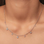 Rhodium-plated sterling silver necklace with delicate cubic zirconia flower charms worn on the neck
