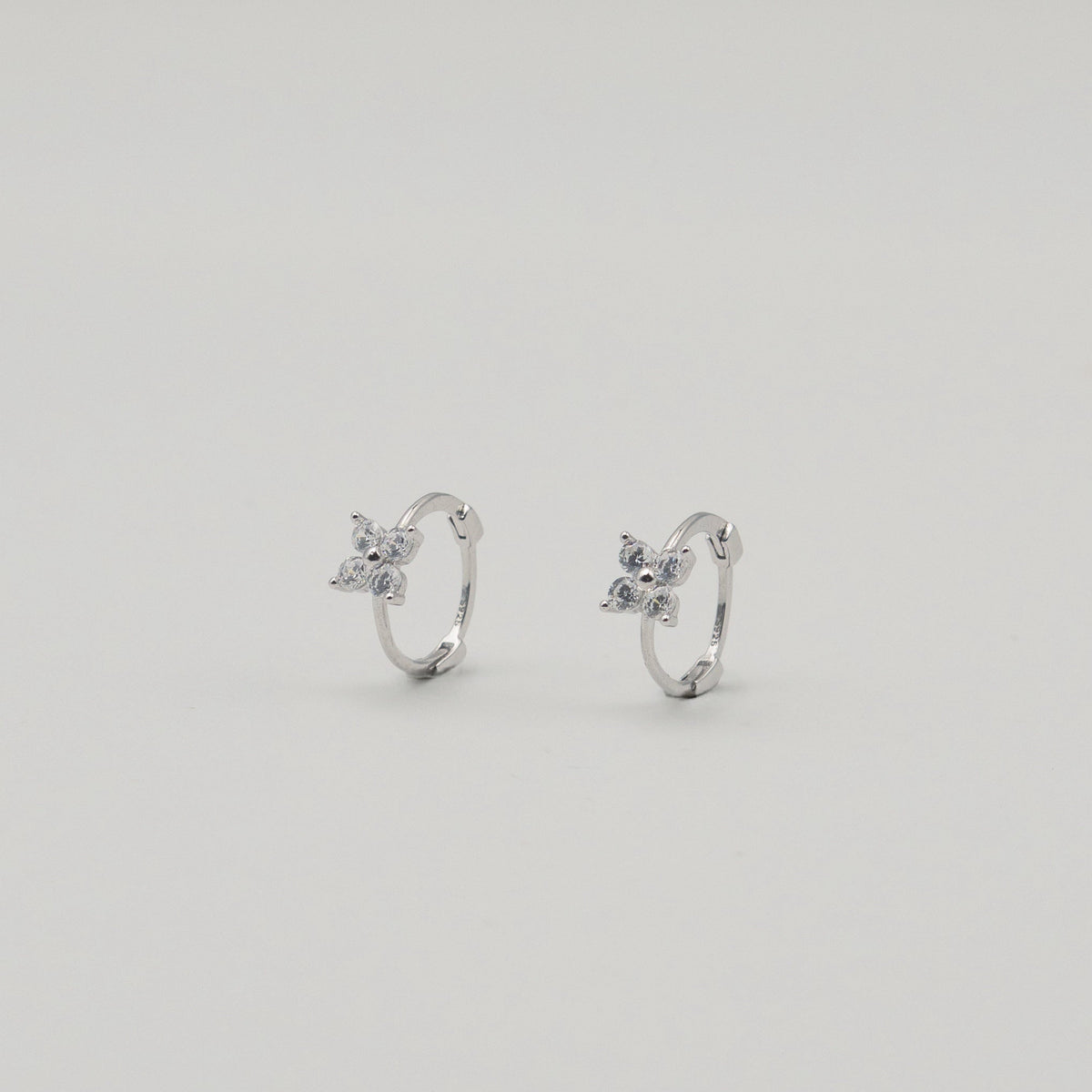 Rhodium-plated sterling silver hoop earrings with four-petal cubic zirconia flower details