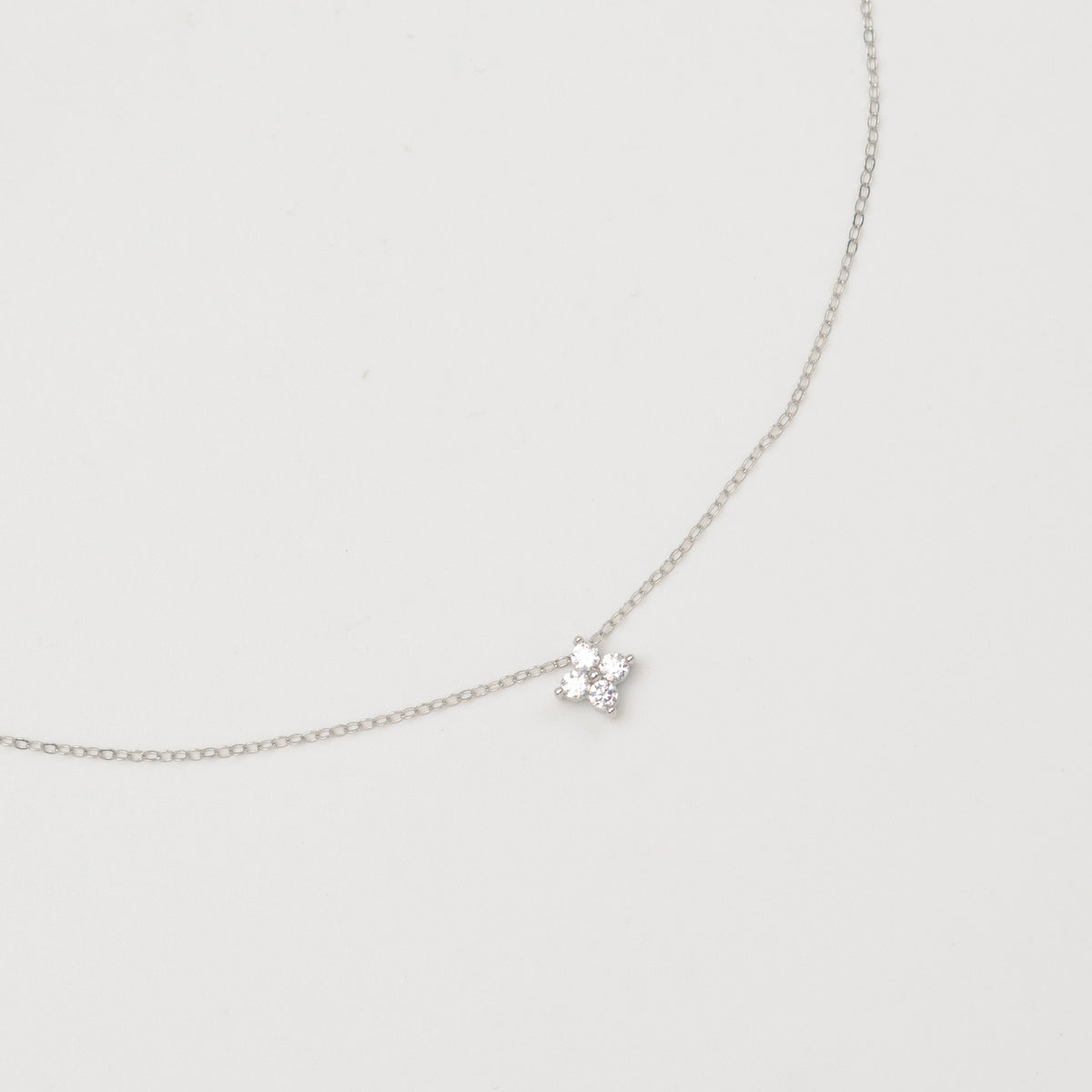 Rhodium-plated sterling silver necklace with a small four-petal cubic zirconia pendant
