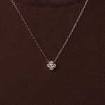 Rhodium-plated sterling silver necklace with four-petal cubic zirconia pendant worn on neck