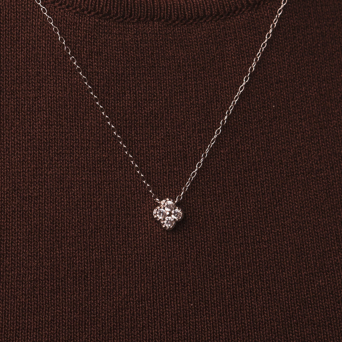 Rhodium-plated sterling silver necklace with four-petal cubic zirconia pendant worn on neck