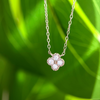Rhodium-plated sterling silver necklace with four-petal cubic zirconia pendant against a green background