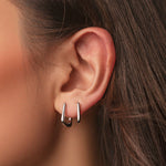 Rhodium-plated sterling silver geometric hoop earrings with a polished finish worn on ear