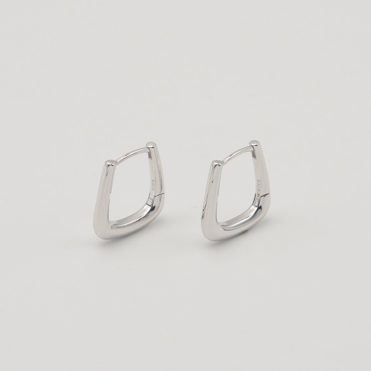 Rhodium-plated sterling silver geometric hoop earrings with a polished finish on a light background